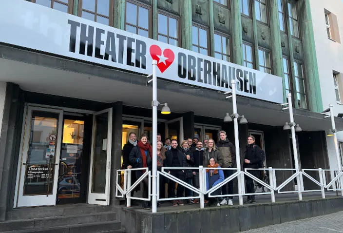 Gruppe steht vor dem Eingang des Theaters Oberhausen unter dem Schriftzug Theater Oberhausen