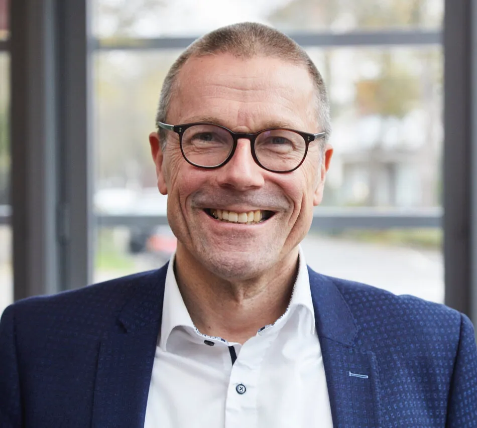 Porträt von Uwe Schneidewind, lächelnder Mann mit Brille im dunkelblauen Sakko