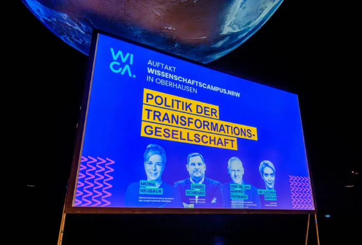 Leinwand zum WICA-Auftakt in Oberhausen mit dem Titel Politik der Transformationsgesellschaft